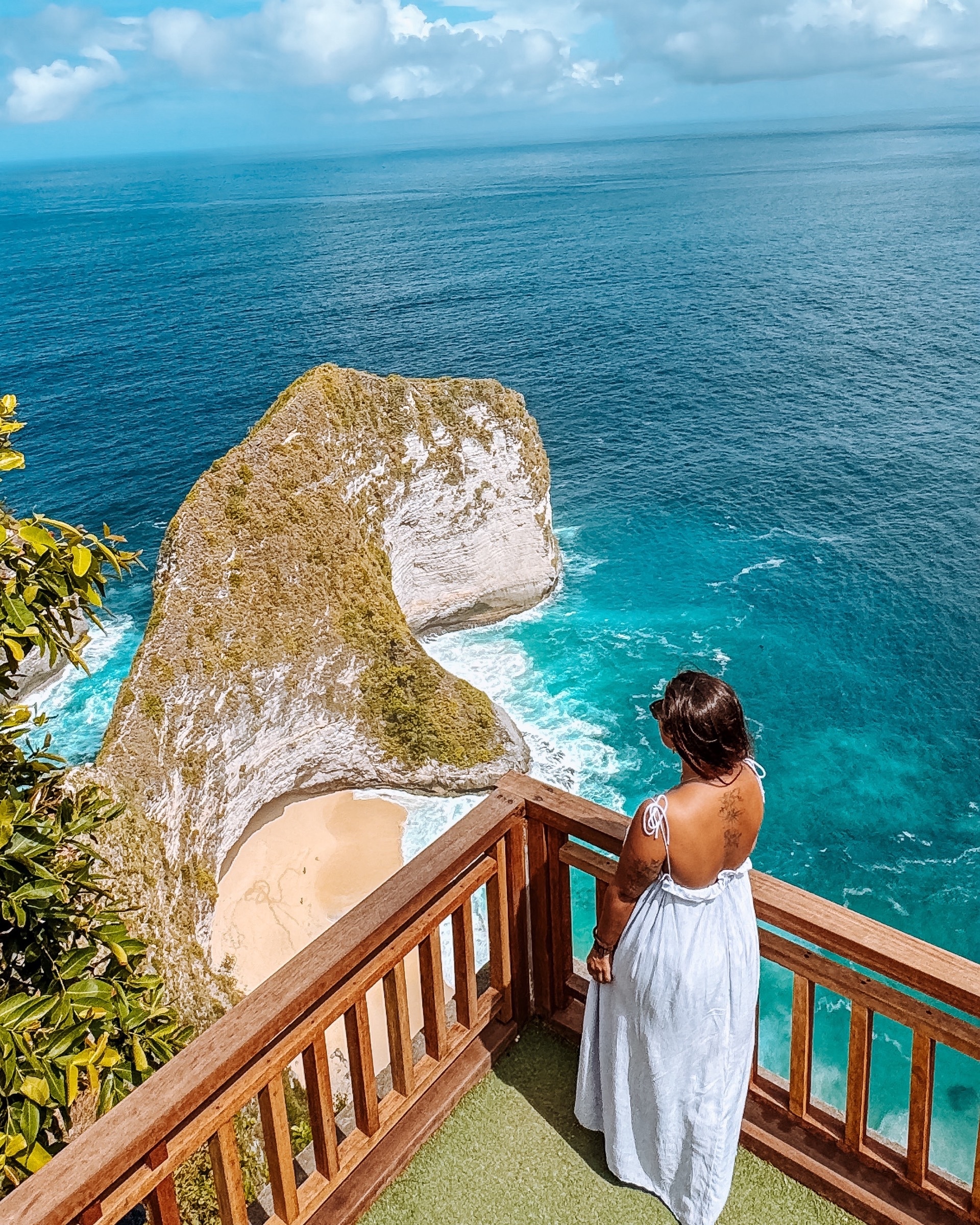 Joana con vestido blanco, de espaldas, sobre el acantilado de Kelingking en Nusa Penida